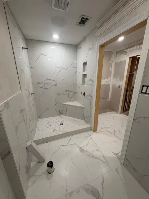 Finished walk-in shower with corner bench and niches