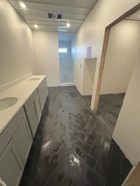 Finished bathroom — double vanity and black tile floor